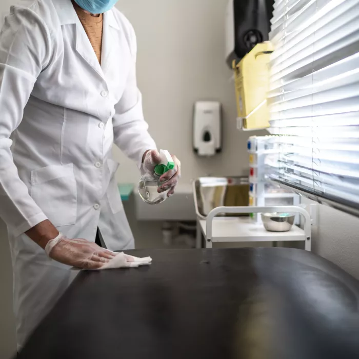 Doctor cleaning gurney with alcohol